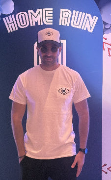 Man posing in front of a 'Home Run' backdrop with a blue and white design.