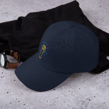 Black cap with a yellow and blue logo on a gray surface with black fabric and watch.