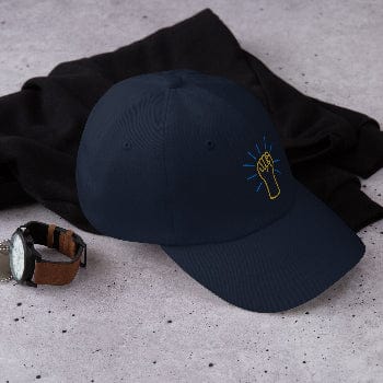 Black cap with a logo on a textured surface next to a black sweater and watch.