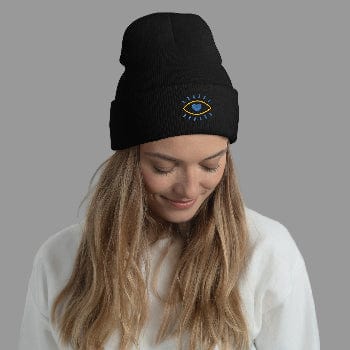 Woman wearing a black beanie with an embroidered design against a light gray background