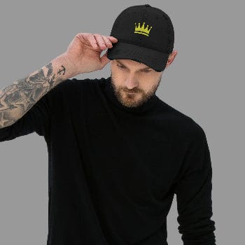 Man wearing a black cap with a yellow crown emblem on a light gray background