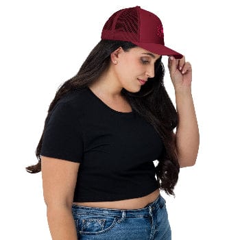 Woman wearing a black crop top and blue jeans with a red cap on a white background