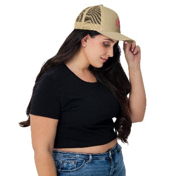 Woman wearing a black crop top, blue jeans, and a beige cap on a white background