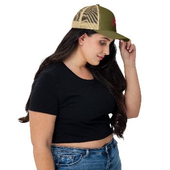 Woman wearing a black crop top, blue jeans, and a green and beige cap on a white background