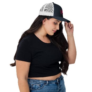 Woman wearing a black crop top, blue jeans, and a black and white cap on a white background