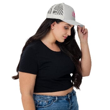 Woman wearing a black crop top and blue jeans with a white cap on a white background