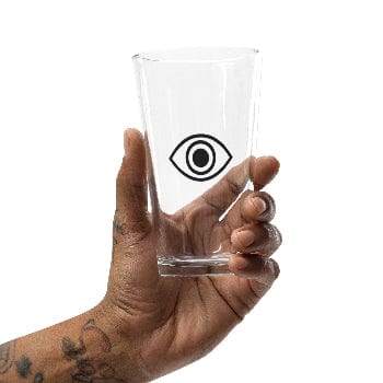 Hand holding a clear glass with an eye symbol design on a white background