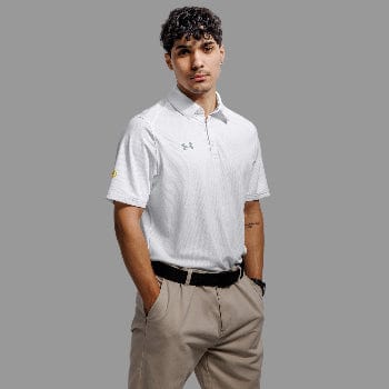 Man wearing a white Under Armour polo shirt and beige pants against a gray background