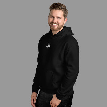Man wearing a black hoodie with a logo against a white brick wall