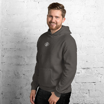 Man wearing a gray hoodie with a ey eye logo against a white brick wall