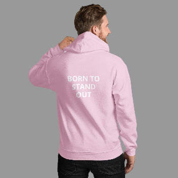 Person wearing a pink hoodie with 'BORN TO STAND OUT' text on the back against a white brick wall.
