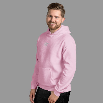 Man wearing a pink hoodie standing against a white brick wall