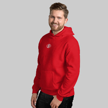 Man wearing a red hoodie with an eye logo against a white brick wall