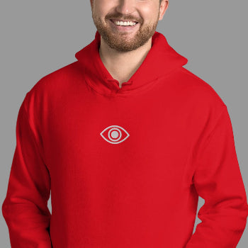 Person wearing a red hoodie with a eye logo on a white brick wall background