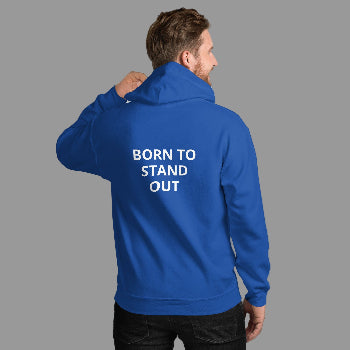 Man wearing a blue hoodie with 'BORN TO STAND OUT' text on the back against a white brick wall.
